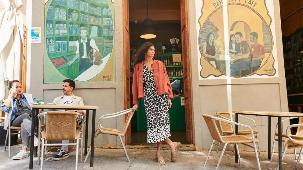 Woman leaning in doorway wearing linen dress and linen jacket